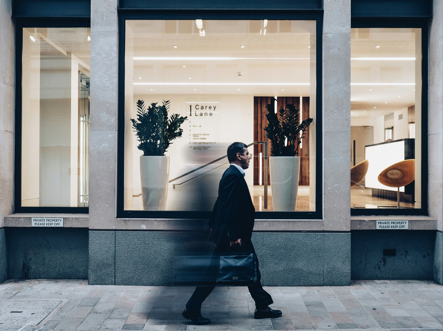 A man in a suit walking past a city law-office storefront