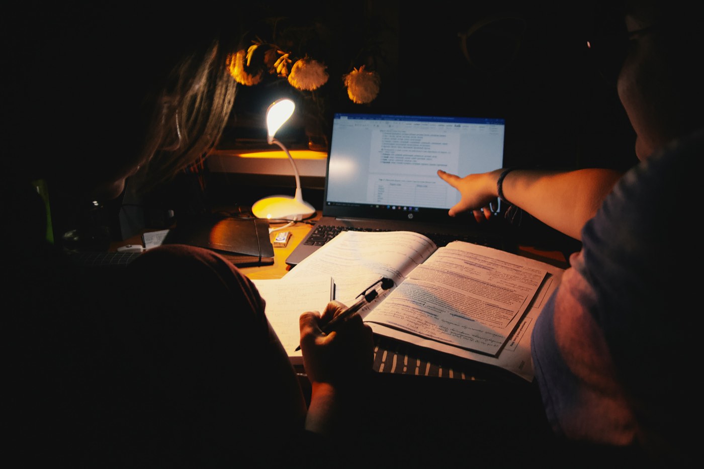 A lawyer working late at night by lamplight with a laptop and open casebook