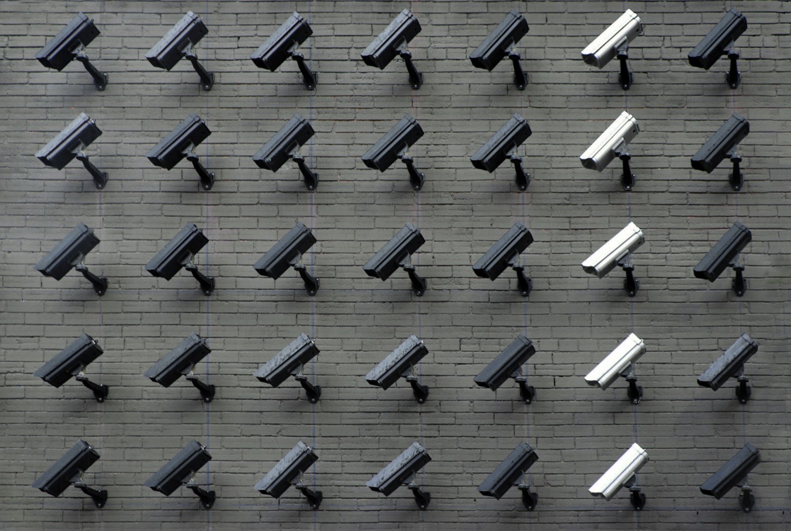 A grid of surveillance cameras mounted on a brick wall